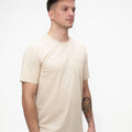 Tricou clasic bej, prim-plan al texturii și cusăturilor de calitate.
